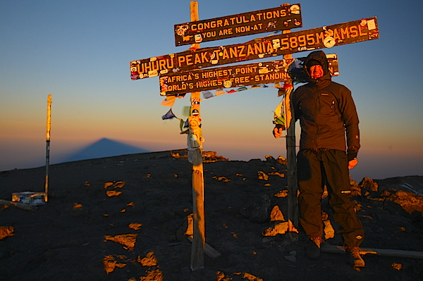 Toppen af Kilimanjaro Uhuru Peak en tidlig morgen, hvor solen kaster bjergets pyramideformede skygge ud i skyerne nedenfor bjerget